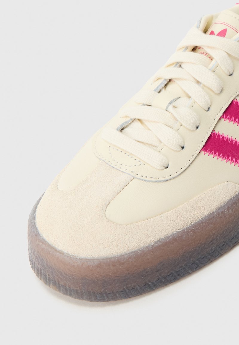 Sneaker color crema e rosa realizzata con materiali in suede e pelle, punta rotonda, suola spessa traslucida e lacci piatti in cotone.