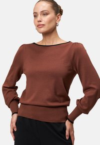 Brązowy sweter z długim rękawem, okrągłym dekoltem, żebrowanym wykończeniem i czarnymi akcentami wzdłuż dekoltu i mankietów. Gładka tekstura, dopasowany krój.