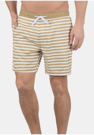 Beige striped badetights med hvite horisontale striper, elastisk linning og snor. Materialet virker lett og glatt.