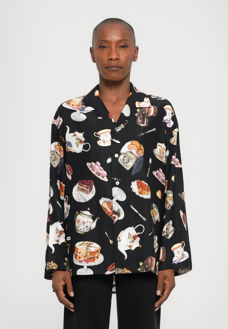 Black shirt featuring a whimsical pattern of teacups, desserts, and utensils. Made of lightweight fabric with a relaxed fit and collared design.