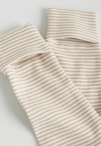 Randiga strumpor i krämfärg och ljusbrun, med ribbade muddar och en mjuk textur. Ränderna är jämnt fördelade för enhetlighet.