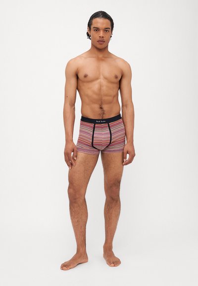 Boxer-briefs rayés colorés avec une ceinture noire arborant un logo. Fabriqués en tissu extensible, ils offrent un ajustement serré et une longueur jusqu'aux mi-cuisse.
