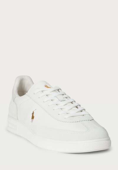 Sneaker bianca in pelle con accenti in suede, lacci e suola testurizzata. Presenta un logo dorato sul lato e un design della punta arrotondata.