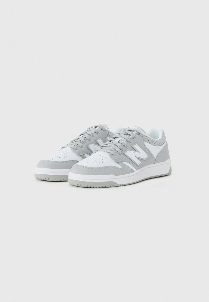 Pair of low-top gray and white sneakers with laces and a stylized "N" logo on the sides, set against a plain background.