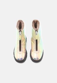Bottines iridescentes avec une texture lisse, dotées d'une fermeture éclair à l'avant et d'une doublure en fausse fourrure douce. Semelle en caoutchouc noir.