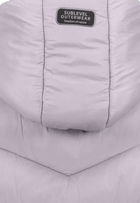 Ljuslila dunjacka med huva, med kavitetsstickning och en svart etikett som s�äger "SUBLEVEL OUTERWEAR." Slät textur.