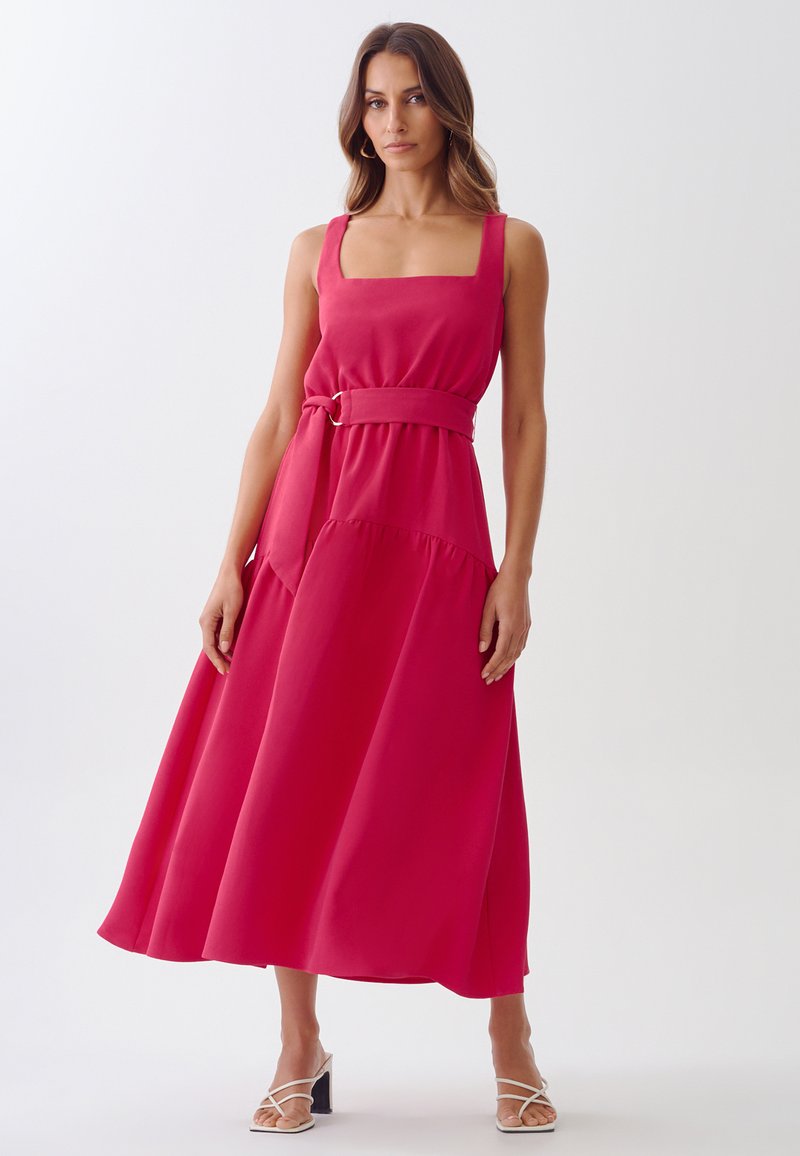 A sleeveless, square-neck, pink maxi dress with a belted waist, A-line silhouette, and layered bottom hem, made from a smooth fabric.