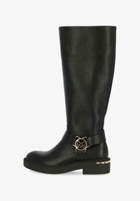 Bota negra hasta la rodilla hecha de cuero suave. Presenta un logotipo dorado en forma de M en una correa negra, punta redonda y un tacón bajo.