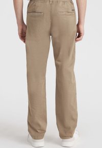 Beige afslappede bukser med elastisk talje, to bagside lommer og indsnørede ben. Lavet af letvægts, åndbart stof.