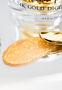 24 Karat Goldcreme auf einem mit Gold besetzten Spatel, mit einer glatten, schimmernden Textur und einer samtigen, reichen goldenen Farbe.