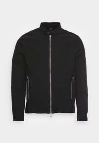 Veste bomber noire en tissu lisse ; dotée d'une fermeture éclair frontale, de poches latérales et d'un col montant avec fermeture à pression.