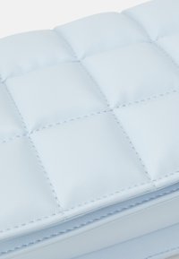 Clutch in pelle trapuntata di un blu chiaro con design a motivo quadrato, caratterizzato da cuciture sottili e una texture liscia per un aspetto raffinato.