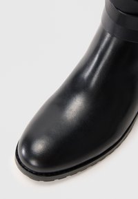 Black leather ankle boot with smooth texture, rounded toe, and a slight sheen. Features a rubber outsole for grip.
