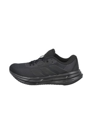 Zapatilla deportiva negra con parte superior de malla, suela acolchada, cordones y tres rayas en el costado. Detalles texturizados en el talón.