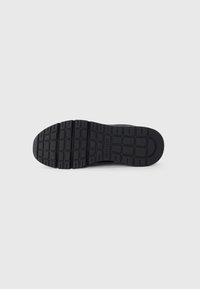 Semelle de sneaker noire en caoutchouc texturé avec un motif de semelle pour une meilleure adhérence. Comprend un marquage sur la partie intermédiaire.