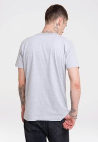 Gray short-sleeve t-shirt made of cotton, featuring a round neckline and a relaxed fit. Visible tattoos on the arm, plain back view.