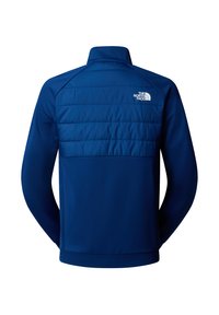 Modrá fleecová bunda s texturovaným designem dlouhého rukávu. Má prošívaný zadní díl a límec, a bílý logo na pravém rameni.