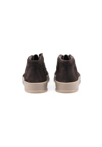 Bottes de cheville en suède marron foncé avec semelle en caoutchouc beige, dotées de coutures minimes et d'un design épuré. Texture lisse avec fermeture éclair à l'arrière.