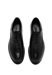 Zapatos brogue de cuero negro con diseño de cordones, punta afilada, perforaciones decorativas y textura suave. Forro interior suave.