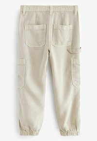 Pantaloni cargo beige con polsini elastici, dotati di due tasche posteriori e tasche laterali. Il materiale sembra resistente e presenta una finitura testurizzata.