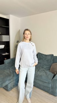 Hele halli tekstuuriga kapuutsiga särk diagonaalse mustriga, millel on kolm nuppu õlal, kokku sobitunud helesiniste laienevate teksadega.