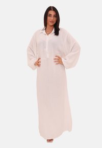 Robe maxi blanche à manches longues en tissu texturé, dotée d'une fermeture à boutons sur le devant, d'une coupe décontractée et de larges manches. Ourlet lisse.