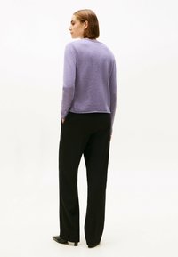 Top de punto de manga larga en lavanda con cuello redondo, combinado con pantalones de pierna ancha negros y zapatos de punta negra. Textura suave, ajuste casual.
