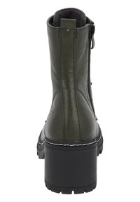 Botín de cuero verde con suela de goma negra gruesa, cremallera lateral y costuras en blanco que contrastan a lo largo del borde de la suela.