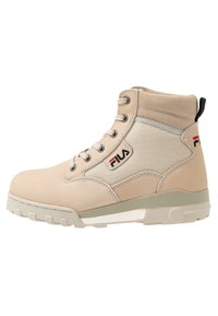 Scarponi da trekking beige con una parte superiore in suede liscio, pannelli in rete e suola in gomma testurizzata. Presentano lacci e un piccolo pull tab nero sul tallone.