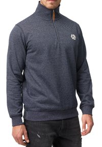 Marine halvlang zip trøje lavet af tekstureret stof, med et logo på brystet, ribbede ærmekanter og en lynlås lukning med en lædertræk.
