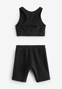Reggiseno sportivo nero a coste con design a racerback e pantaloni corti a vita alta coordinati, entrambi con materiale testurizzato e bordi senza cuciture.