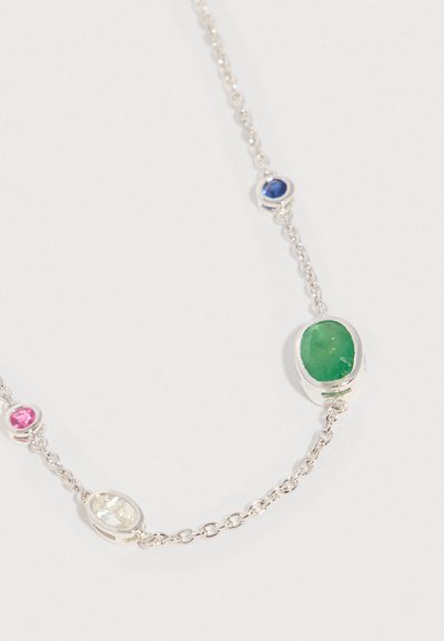 Stříbrný náhrdelník s oválnými růžovými, čirými, modrými a zelenými drahokamy zasazenými do lunet na bílém pozadí.