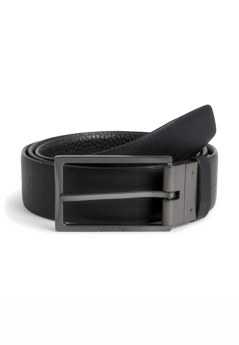Cinturón de cuero negro con un acabado texturizado, que presenta una hebilla rectangular de plata y grabado de la marca. Forma curva, longitud ajustable.