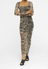 Lång, figursydd klänning med ett leopardmönster i nyanser av brunt och svart, med långa ärmar och fyrkantig halsringning. Slät textur.