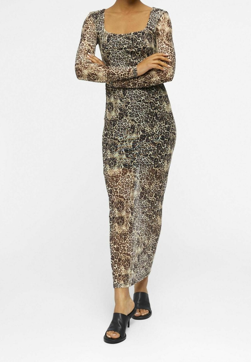 Lång, figursydd klänning med ett leopardmönster i nyanser av brunt och svart, med långa ärmar och fyrkantig halsringning. Slät textur.