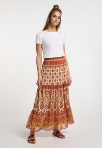 Maxi-jurk in beige met bloemen- en paisleymotieven in rood en oranje. Lichte stof met een gelaagde, gerimpelde zoom. Gepaarde met een witte top.