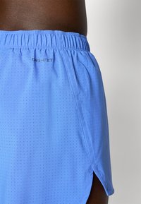 Blaue Dri-FIT Sportshorts mit durchbrochener Textur, elastischem Bund und seitlichen Schlitzen für Bewegungsfreiheit.