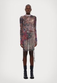 Robe longue à manches longues en tissu transparent avec des tourbillons floraux multicolores. Col haut, silhouette ajustée, fentes sur les côtés et un tissu léger et texturé.