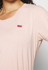 T-shirt rosa chiaro a maniche corte realizzato in tessuto morbido, con un patch del logo rosso Levi's nella zona sinistra del petto.
