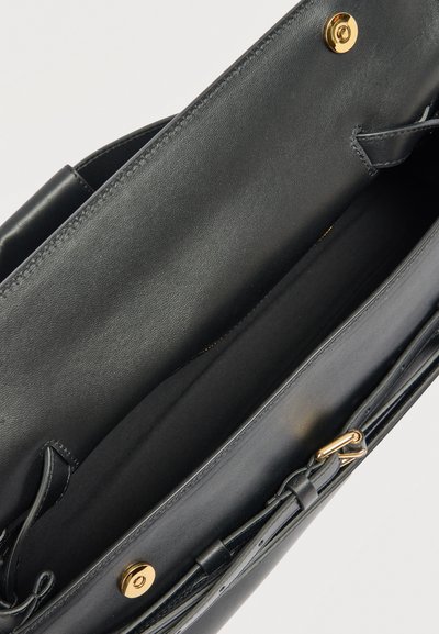 Μαύρη δερμάτινη τσάντα χειρός ανοιχτή, με ευρύχωρο εσωτερικό, κλείσιμο με χρυσό κουμπί και ρυθμιζόμενο λουρί με χρυσή αγκράφα.