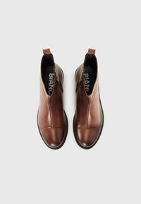 Bottes à cheville en cuir marron avec une finition lisse, fermeture éclair sur le côté, bout arrondi et talon renforcé. Logo de la marque visible à l'intérieur.