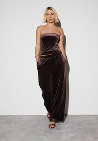 Bordeaux fluwelen twee-delige outfit met een strapless top en wijde pantalon met een elastische tailleband. Hoge kwaliteit textuur en minimale accenten.