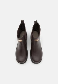 Brown leather ankle boots with a smooth finish, side elastic panels, and a decorative metallic accent. Flat rubber sole for traction.