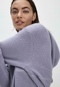 Lila Fleece-Hoodie mit strukturiertem Oberflächendesign, lockerer Passform, langen Ärmeln und großer Kapuze, die aus weichem Material gefertigt ist und einen lässigen Stil bietet.