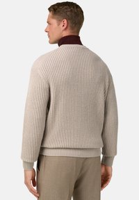 Pull en maille beige avec des poignets et un ourlet côtelés, doté d'un col roulé bordeaux profond. Texturé avec un motif en grille sur le corps.