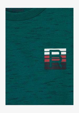 Zelena majica s teksturom koja ima rebrasti izrez i pravokutni logotip s horizontalnim trakama u bijeloj, crvenoj i crnoj boji, centriran na prsima.