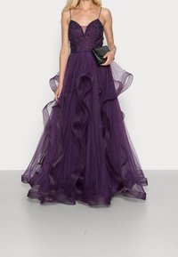 Fioletowa wieczorowa suknia z dopasowanym koronkowym gorsetem, delikatnymi ramiączkami oraz zwiewną halką z tiulu, zakończoną falbanami.