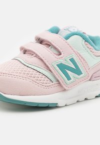 Light pink sneaker with mesh and suede materials. Features turquoise accents, Velcro straps, and a prominent "N" logo on the side.