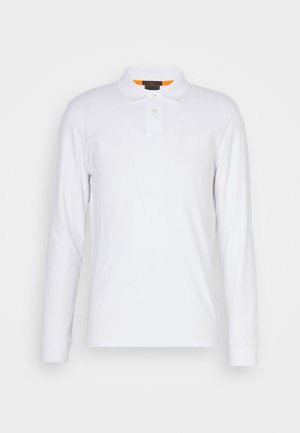 Vit långärmad polo skjorta av bomull, med spetskrage, tvåknappsstängning och en liten logotyp på bröstet. Orange accent innanför kragen.