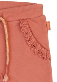 Persikofärgade sweatpants med en texturerad spetsdetalj på fickan och en flätad dragsko med guldtråd i midjan.